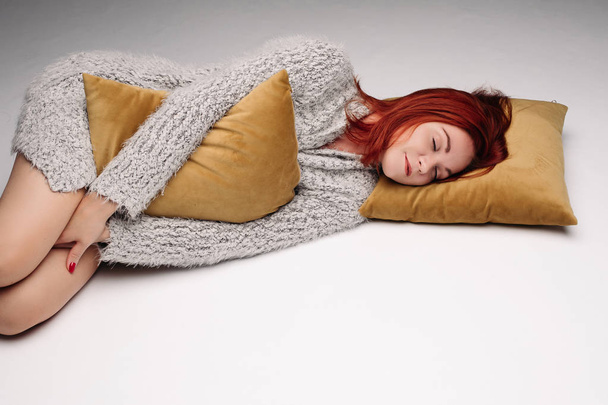 Portrait studio d'une femme en pull serrant un oreiller
. - Photo, image