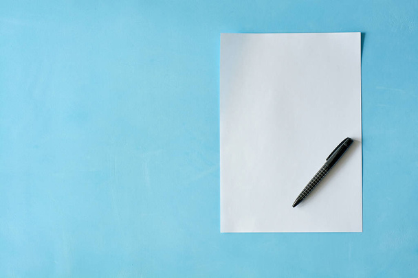 Λευκό φύλλο χαρτί με μαύρη πένα ισόφυτη στο γαλάζιο φόντο.. - Φωτογραφία, εικόνα
