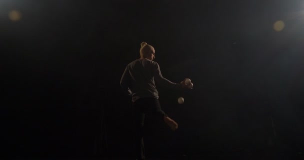 Stílusos zsonglőr a színpadon dobja labdát a lábát a karját. T - Felvétel, videó