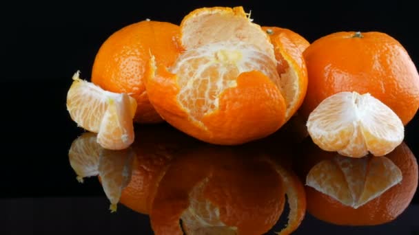 Dojrzałe pomarańczowe mandarynki na lustrzanym podłożu na czarnym tle. - Materiał filmowy, wideo