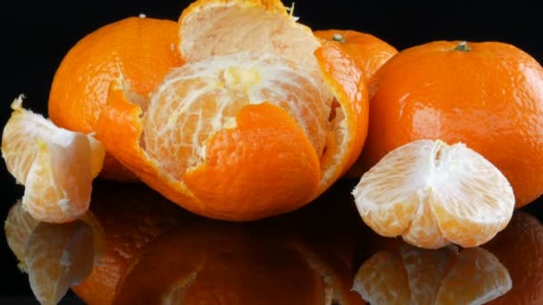 Dojrzałe pomarańczowe mandarynki na lustrzanym podłożu na czarnym tle. - Materiał filmowy, wideo