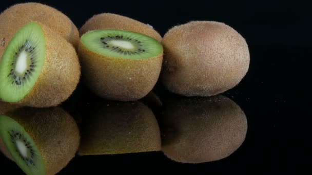 Stylish view of ripe sliced and whole kiwi fruit on a mirror surface on black background in the studio - Footage, Video