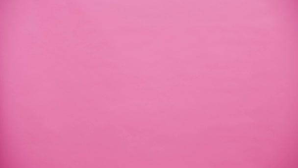 Young couple standing on pink background. During this time they are dressed in a hook. Looking at each other, talking and smiling and kissing. - Filmagem, Vídeo