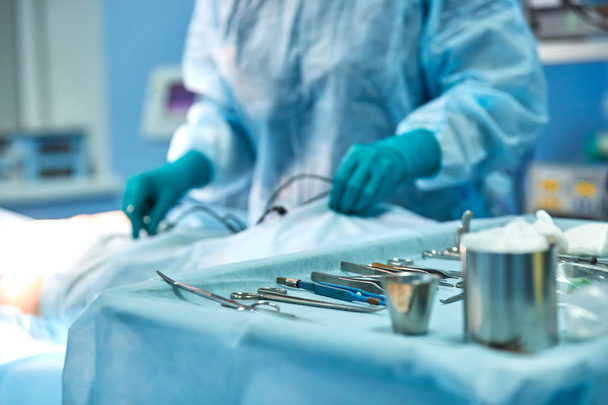 Подготовка стерильного инструмента для хирургии. Аккуратно выложенный инструмент на фоне подготовки хирургов к операции, концепция хирургии
 - Фото, изображение