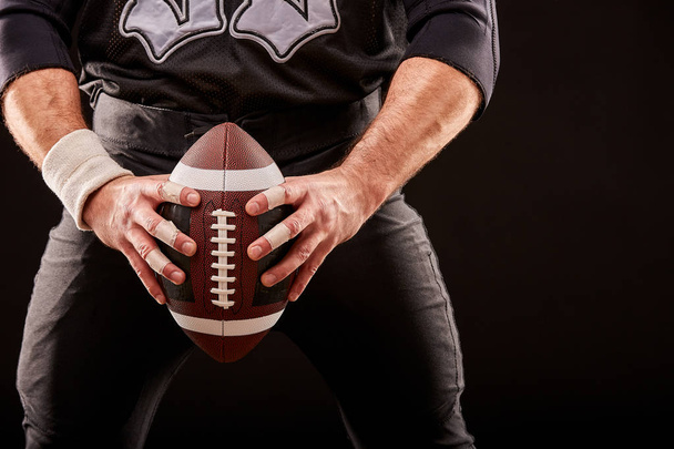 American football speler van de sporter op stadion met lampjes op zwarte achtergrond. - Foto, afbeelding
