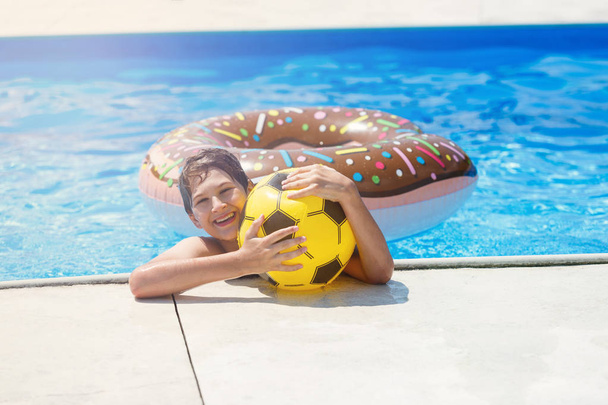 glücklich niedlichen kleinen Jungen Teenager im Schwimmbad. Aktive Spiele auf dem Wasser, Urlaub, Ferienkonzept. Schokoladen-Donut. coole Sommerferienspaß für Kinder. - Foto, Bild