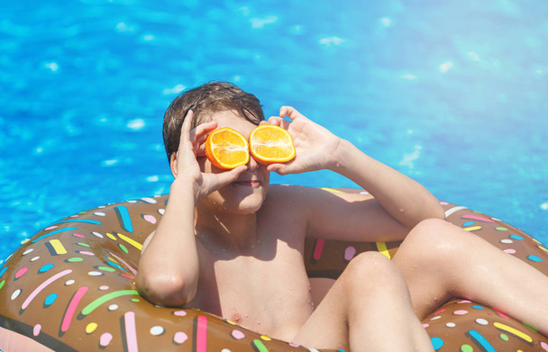 Happy cute little boy teenager in swimming pool. Active games on water, vacation, holidays concept. Chocolate donut. Cool fun summer holidays for children. - Fotoğraf, Görsel