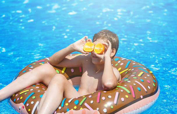 Joyeux petit garçon adolescent dans la piscine. Jeux actifs sur l'eau, vacances, concept de vacances. Un beignet au chocolat. Cool fun vacances d'été pour les enfants
. - Photo, image