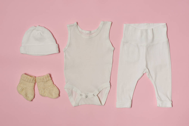 ピンクの背景の赤ちゃんファッション概念。キャップ、ボディー スーツ、パンツ、ソックス. - 写真・画像