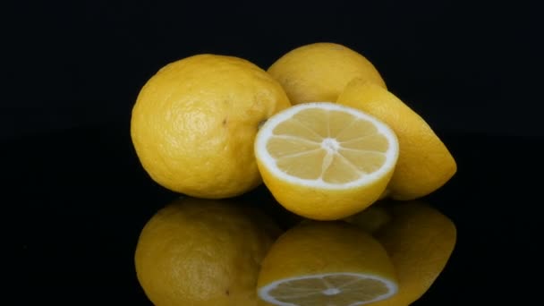 Grands citrons jaunes frais sur une surface miroir noire sur un fond noir
. - Séquence, vidéo