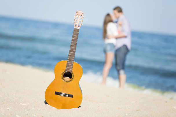 若い男とビーチとギターの上の女性の肖像画 - 写真・画像