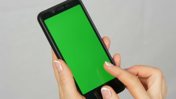 Dobře-pečlivě udržované ženské ruce s krásnou manikúru jsou vybaveny černým smartphone se zelenou obrazovkou nebo chromovým klíčem na bílém pozadí ve studiu - Záběry, video