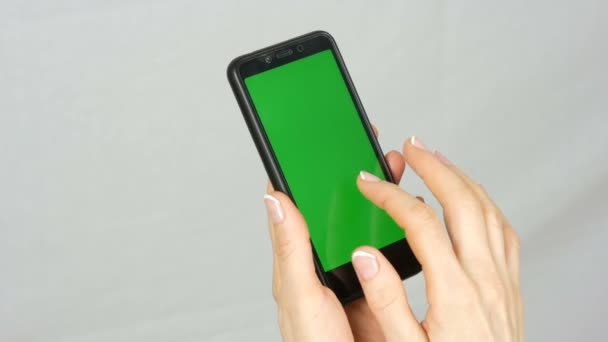 Zadbane schludne kobiece ręce z pięknym manicure trzymać czarny smartfon z zielonym ekranie lub chrom klucz na białym tle w Studio - Materiał filmowy, wideo