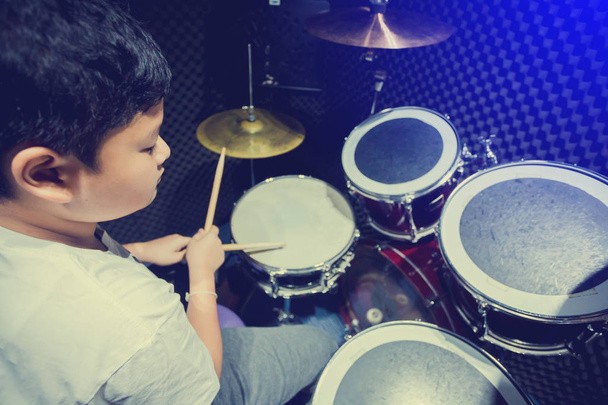 Asian boy put white t-shirt learning and play drum set with wood - Photo, Image