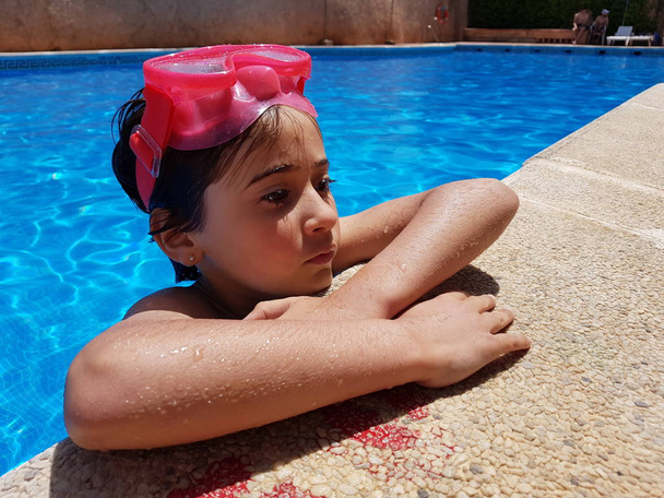 Kleines Mädchen badet mit Taucherbrille im Pool - Foto, Bild