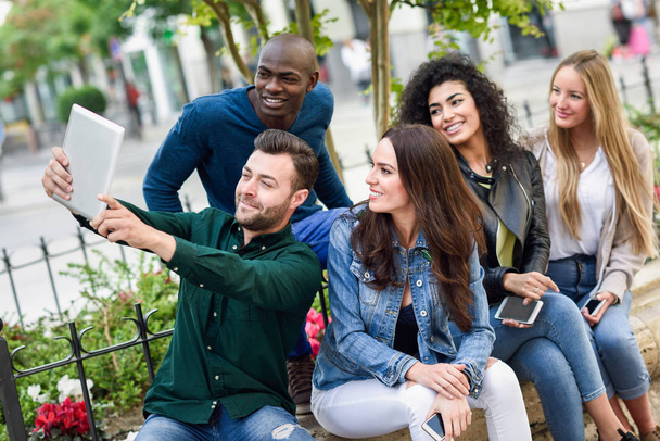 Monietniset nuoret, jotka ottavat yhdessä selfien kaupunkitaustalta
 - Valokuva, kuva
