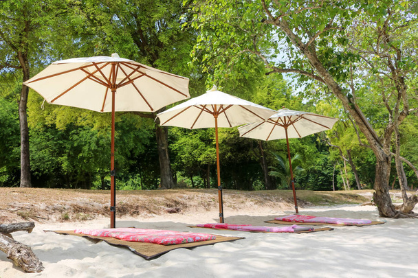 Parapluie blanc avec sacs de haricots et tapis sur la plage à tropical i
 - Photo, image