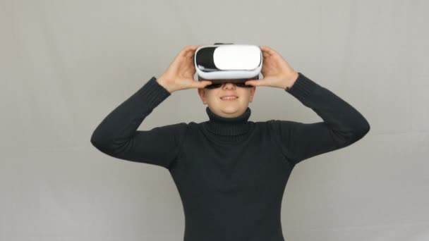 Teenager-Junge schaut in weiße Virtual-Reality-Brillen oder Vr und hat Spaß auf weißem Hintergrund im Studio. Zukunft ist jetzt. - Filmmaterial, Video