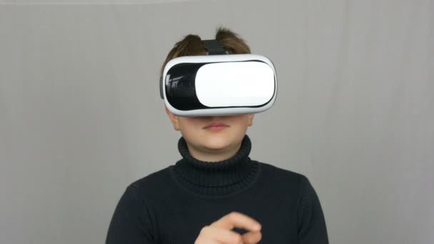 Adolescent garçon regarde dans les lunettes de réalité virtuelle blanche ou VR et s'amuse sur un fond blanc dans le studio. L'avenir est maintenant
. - Séquence, vidéo
