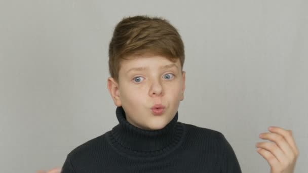 Πορτρέτο ενός αστεία ξανθιά και μπλε-μάτια έφηβο αγόρι που δείχνει καταδίκη με χειρονομίες και εκφράσεις του προσώπου σε λευκό φόντο. Τα συναισθήματα των εφήβων - Πλάνα, βίντεο
