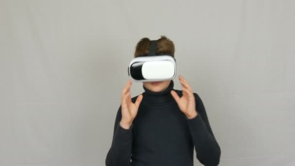 Подросток смотрит в белые очки виртуальной реальности или VR и веселится на белом фоне в студии. Будущее за нами
. - Кадры, видео