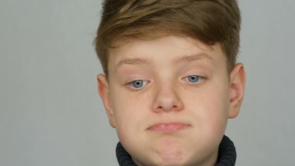 Portret van een grappige Blonde en blauwe ogen tiener jongen die veroordeling met gebaren en gezichtsuitdrukkingen op witte achtergrond toont. Emoties van tieners - Video