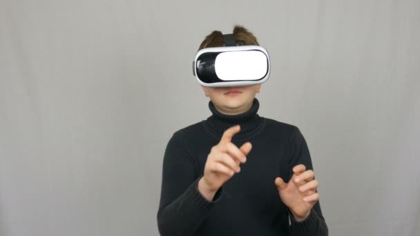 Tiener jongen kijkt in witte virtual reality bril of VR en heeft plezier op een witte achtergrond in de Studio. Toekomst is nu. - Video