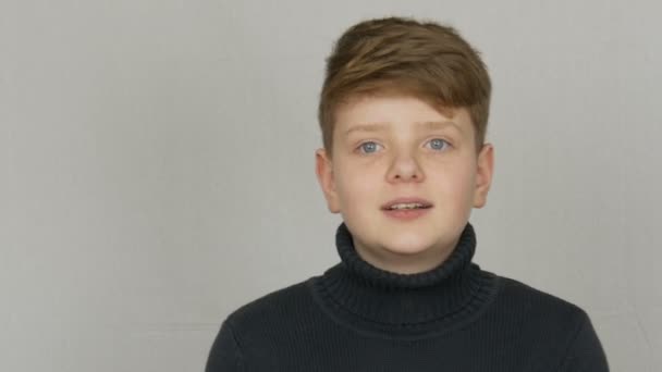 Πορτρέτο ενός αστεία ξανθιά και μπλε-μάτια έφηβο αγόρι που δείχνει καταδίκη με χειρονομίες και εκφράσεις του προσώπου σε λευκό φόντο. Τα συναισθήματα των εφήβων - Πλάνα, βίντεο