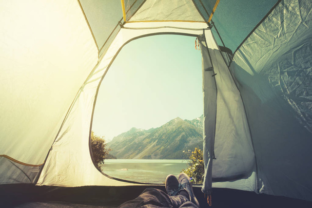Láb ember pihentető élvezi hegyek és a tó Nézd a bejárat szabadtéri utazási életmód fogalma kaland nyaralás szabadtéri kemping sátor - Fotó, kép