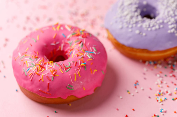 Concept of cooking, baking and food - close-up. Two donuts in pink and violet glaze on a pink background. Trend colors. - Foto, imagen