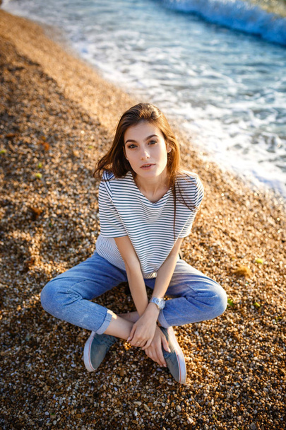 Kumlu sahilde oturan genç güzel güzel kız. - Fotoğraf, Görsel