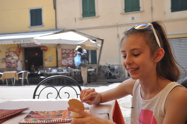 Подросток с длинными волосами ест мороженое в ресторане в Пизе
 - Фото, изображение