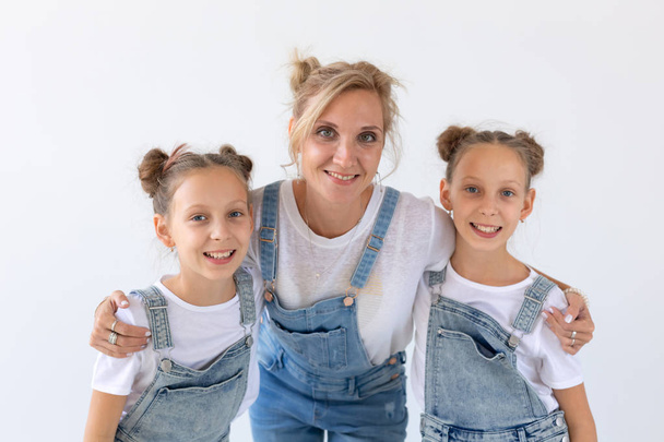 人々、家族や子供たちのコンセプト - 白い背景の上のママの双子の姉妹 - 写真・画像