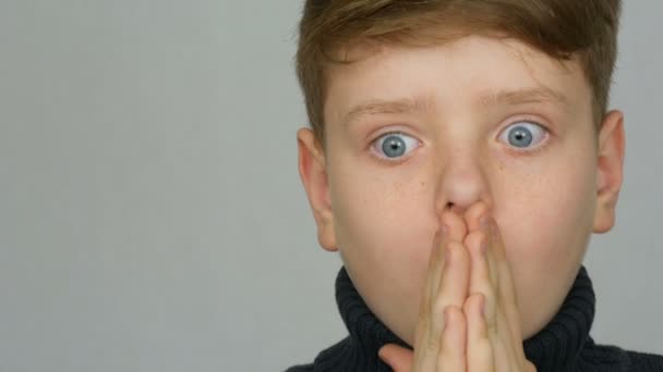 Πορτρέτο του ένα αστείο κοκκινομάλλα έφηβος αγόρι με μπλε μάτια και φακίδες που είναι έκπληκτος σε ένα λευκό φόντο στο στούντιο - Πλάνα, βίντεο