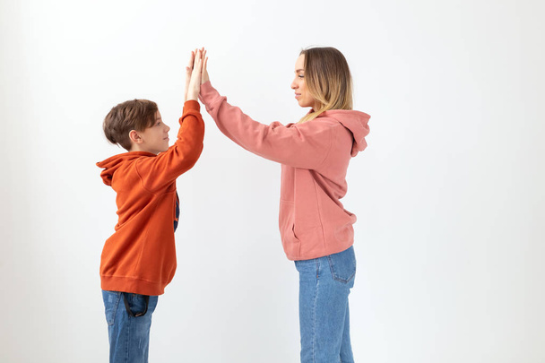 Relatie, Moederdag, kinderen en familie concept - tiener jongen geven hoge vijf aan zijn moeder op witte achtergrond - Foto, afbeelding