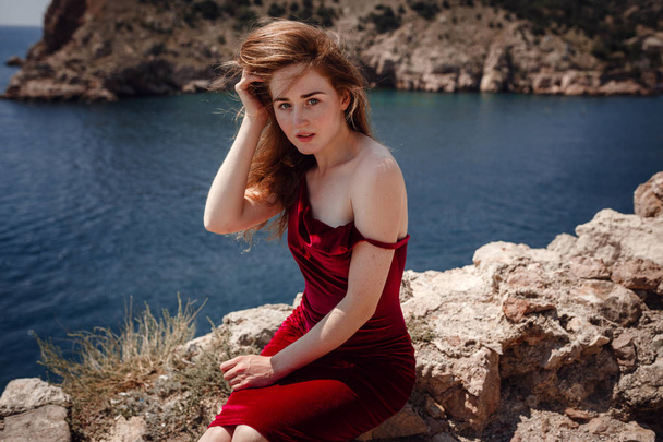 Une belle femme rousse est assise sur un rocher
 - Photo, image