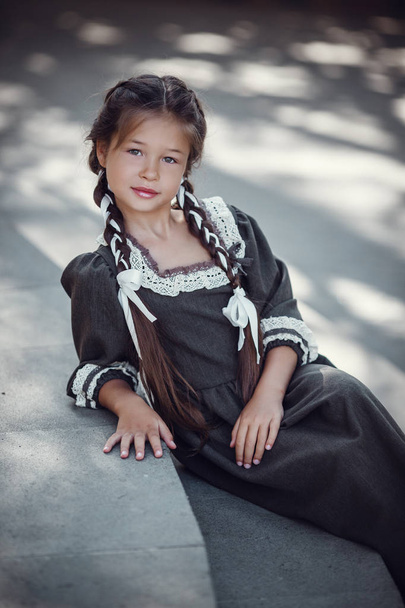 Belle petite fille dans une vieille robe sur le fond de l'architecture du centre historique
 - Photo, image