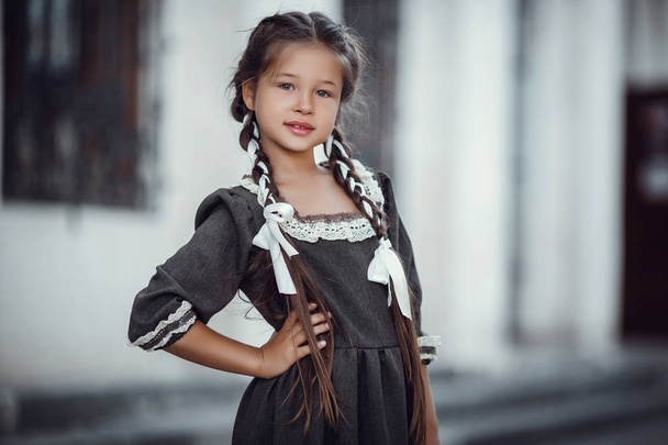 schöne kleine Mädchen in einem alten Kleid vor dem Hintergrund der Architektur des historischen Zentrums - Foto, Bild
