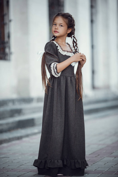 Piękna dziewczynka w starej sukni na tle architektury zabytkowego centrum - Zdjęcie, obraz
