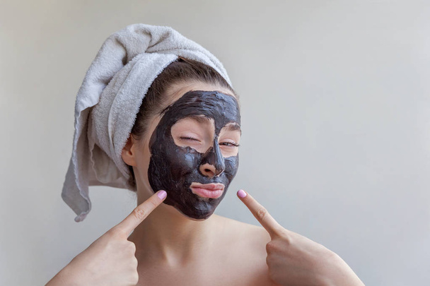 Γυναίκα εφαρμόζοντας μαύρο θρεπτική μάσκα στο πρόσωπό - Φωτογραφία, εικόνα