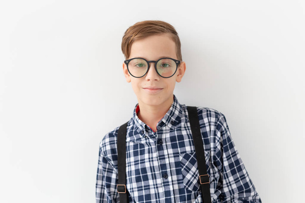 teenager, children and fashion concept - kid dressed in plaid shirt posing over white background - Zdjęcie, obraz