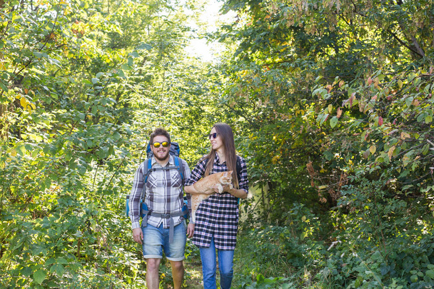 Travel, adventures, hike, tourism and nature concept - Tourist couple with cat walking in the woods - Valokuva, kuva