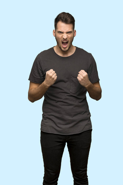 Man with black shirt frustrated by a bad situation over blue background - Fotoğraf, Görsel