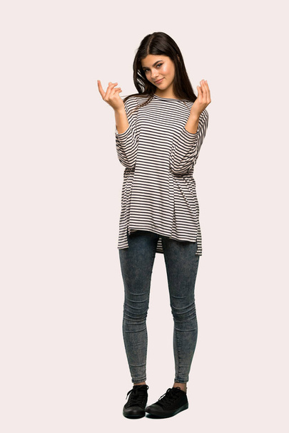 Un full-length tiro di un adolescente ragazza con camicia a righe fare soldi gesto su sfondo isolato
 - Foto, immagini