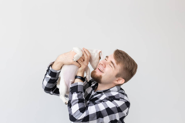 concept de personnes, animaux et animaux - jeune homme tenant Jack Russell terrier chiot sur fond blanc
 - Photo, image