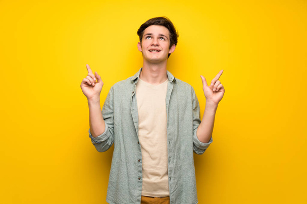 Adolescente uomo sopra il muro giallo che punta con il dito indice una grande idea
 - Foto, immagini