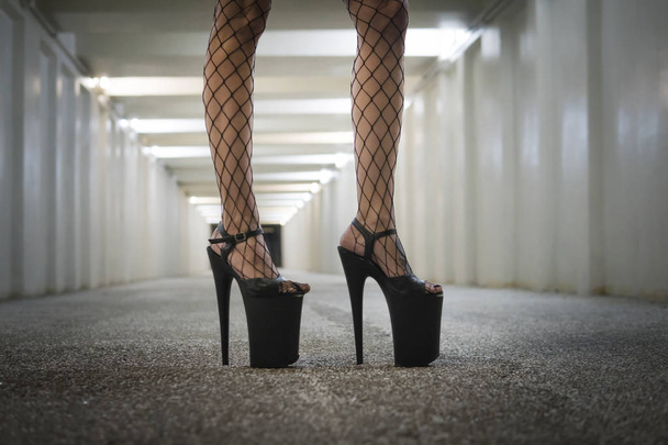 schwarze Schuhe mit sehr hohen Absätzen. eine Frau mit schönen schlanken Beinen steht im Tunnel in der Unterführung - Foto, Bild