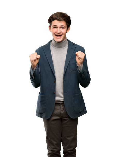 Teenager man with turtleneck celebrating a victory in winner position over isolated white background - Fotó, kép