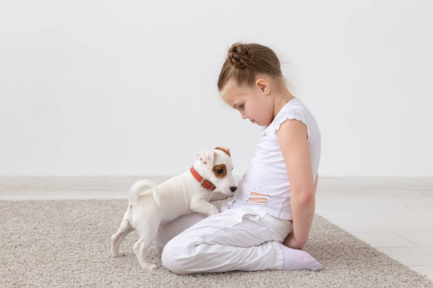 Kedvtelésből tartott állatok és állati fogalma - gyermek lány Jack Russell Terrier kiskutya játszik - Fotó, kép