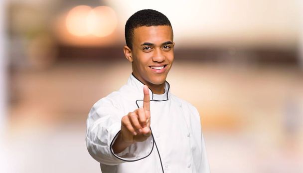 Fiatal afro-amerikai szakács ember mutatja, és szüntesse meg az ujját a céltalan háttér - Fotó, kép